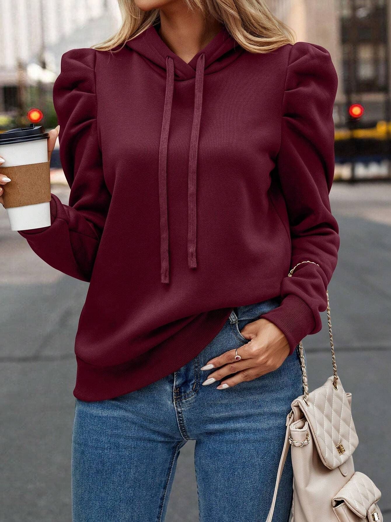 Burgundy cotton-blend hoodie featuring slim-fit silhouette, puff sleeves, and drawstring hood worn with blue jeans.