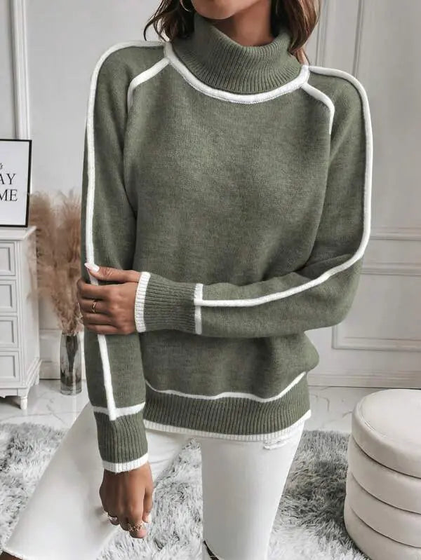Olive green turtleneck sweater with white contrast piping, ribbed cuffs, and a plush knit texture worn with white jeans.