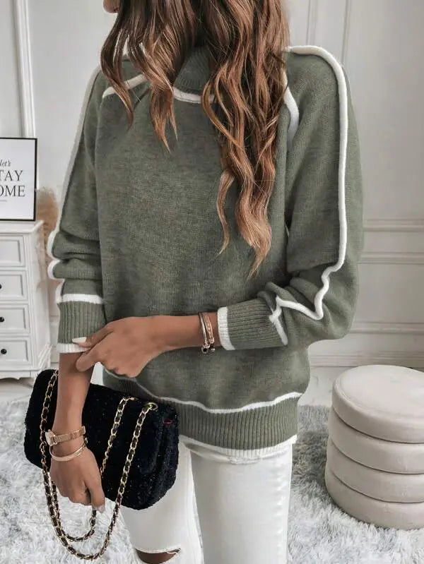 Olive green turtleneck sweater with white contrast piping, ribbed cuffs, and a plush knit texture worn with white jeans.
