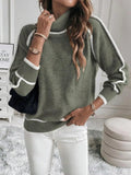 Olive green turtleneck sweater with white contrast piping, ribbed cuffs, and a plush knit texture worn with white jeans.