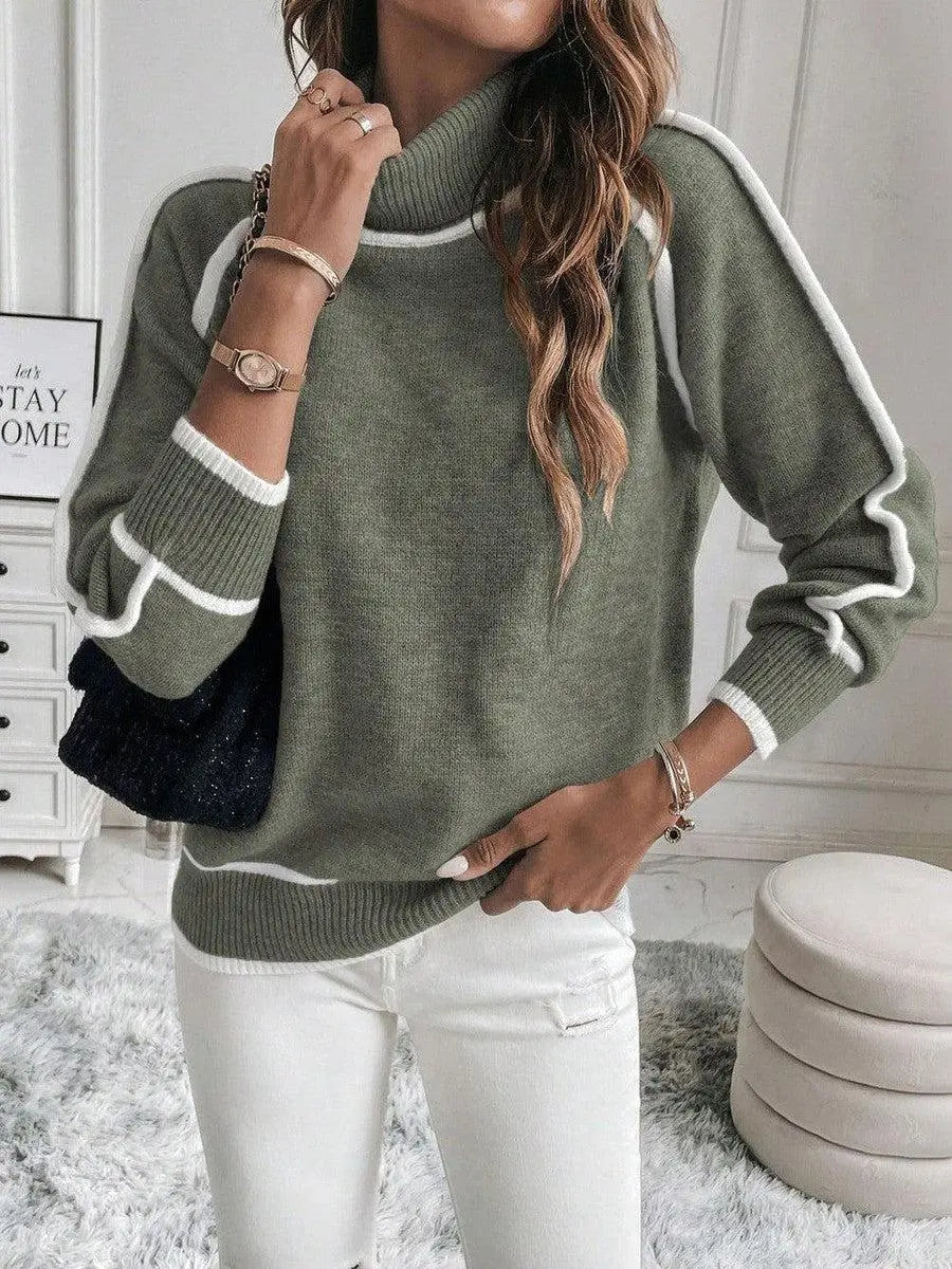 Olive green turtleneck sweater with white contrast piping, ribbed cuffs, and a plush knit texture worn with white jeans.
