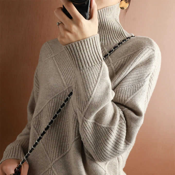 Beige wool turtleneck sweater featuring a raised diamond-pattern knit, ribbed cuffs, and a structured high collar.