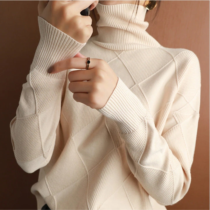 Cream wool turtleneck sweater featuring a raised diamond-pattern knit, ribbed cuffs, and a structured high collar.