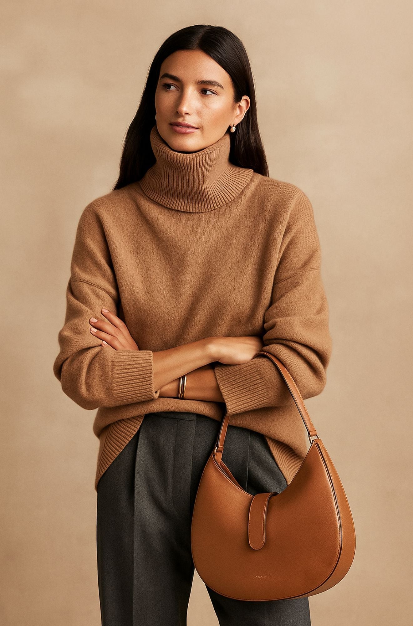 Camel oversized turtleneck sweater featuring a relaxed fit, dropped shoulders, and ribbed cuffs, paired with dark trousers.
