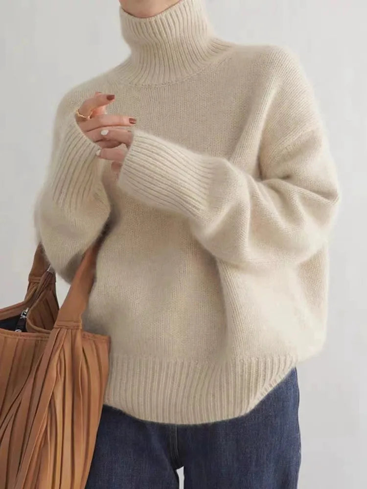 Cream brushed knit turtleneck sweater with an oversized fit, ribbed cuffs, and hem, styled with dark denim and a tan bag.