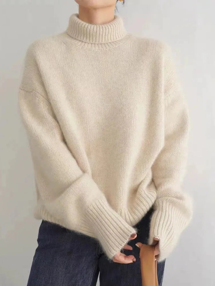 Oversized cream brushed knit turtleneck sweater with ribbed cuffs and hem worn with dark denim jeans.