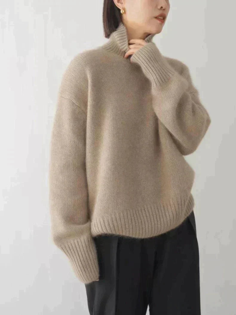 Beige brushed knit turtleneck sweater with a relaxed, oversized fit, high collar, and ribbed cuffs against a white background.