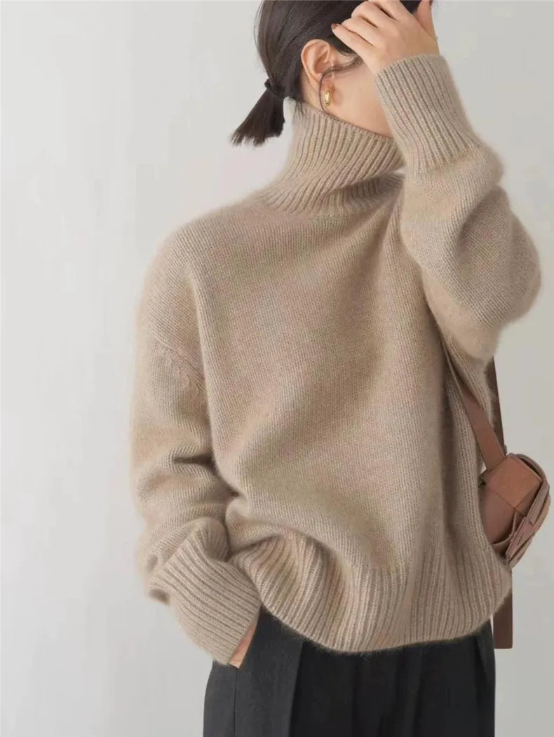Beige brushed knit turtleneck sweater with a relaxed, oversized fit and ribbed cuffs against a neutral background.