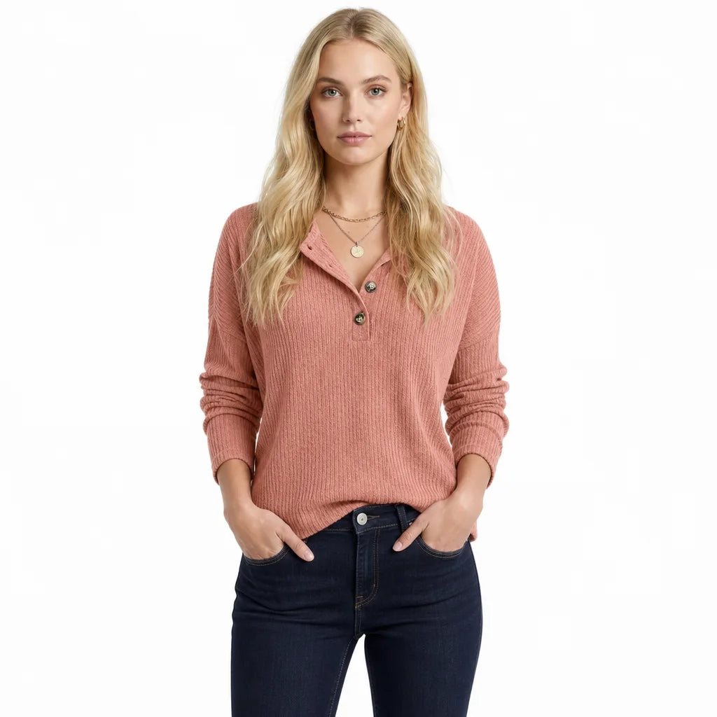 Dusty rose ribbed knit henley sweater with a half-button placket, relaxed fit, and long sleeves worn with dark jeans.