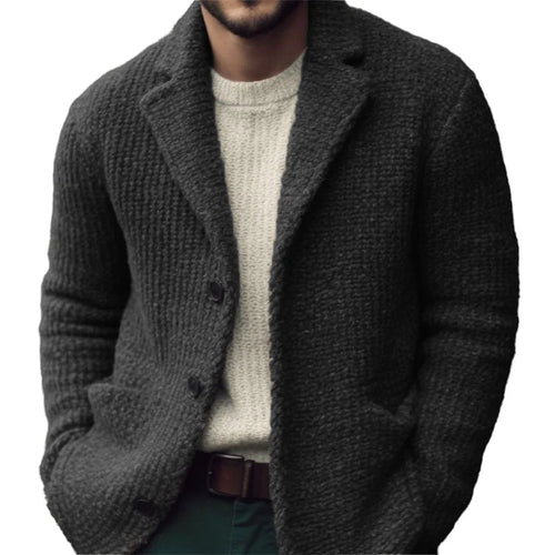 Charcoal grey textured knit cardigan with a notch collar, button front, and patch pockets layered over a cream sweater.