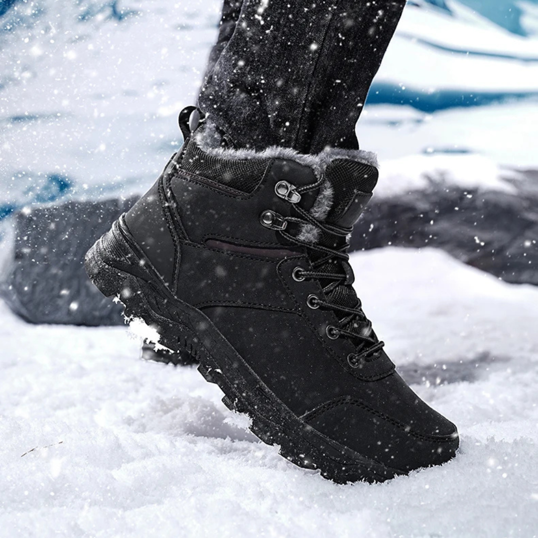 Black vegan leather snow boots for men in falling snow, showing the lace-up front and lug tread