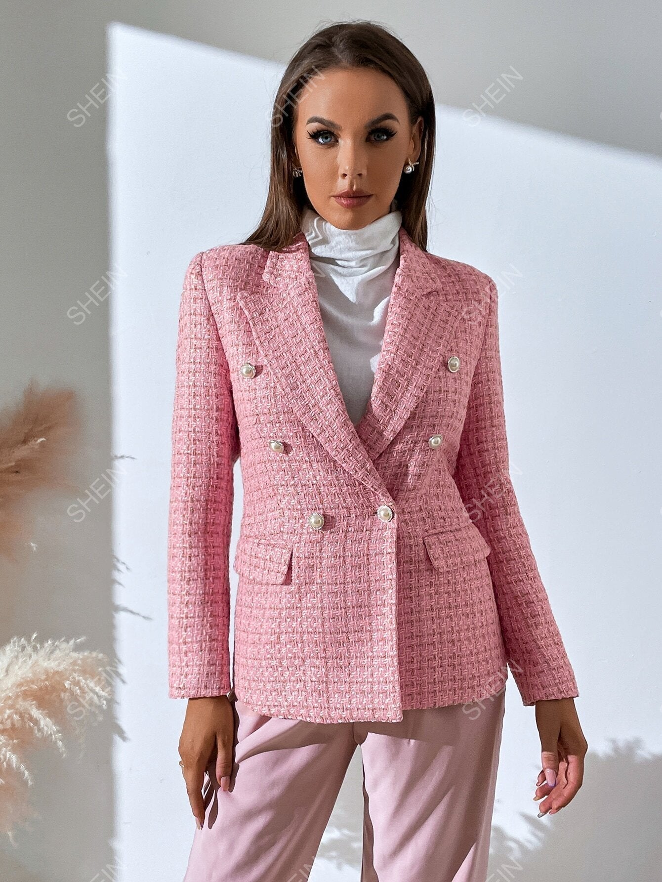 Pink tweed double-breasted blazer with notched lapels, pearl-style buttons, and a tailored, contoured fit.