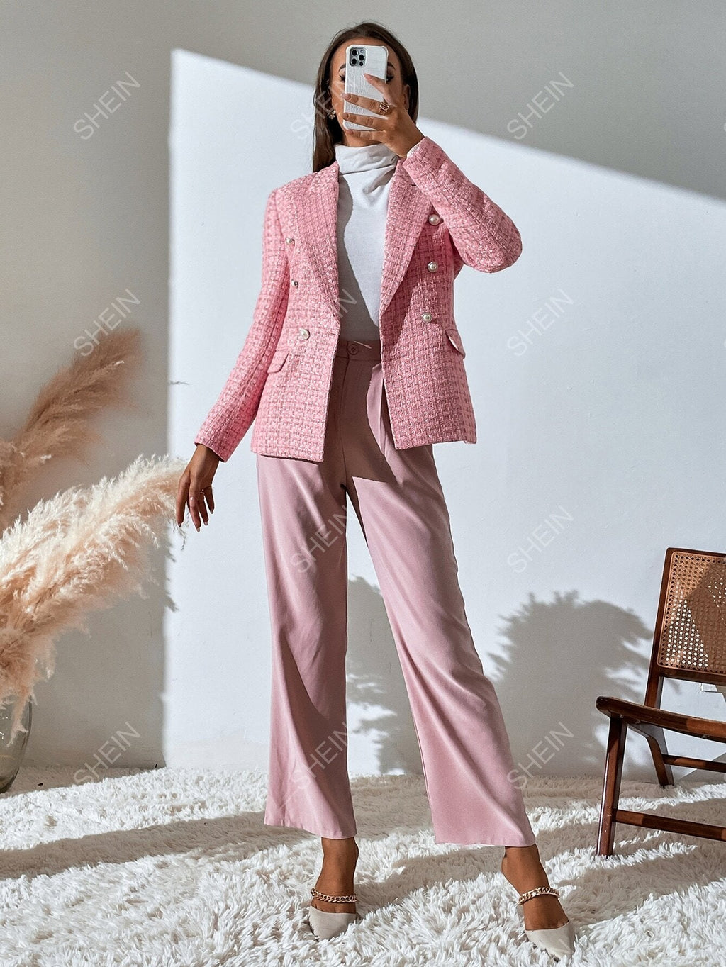 Pink tweed double-breasted blazer with notched lapels and accent buttons, worn with matching trousers and a white top.