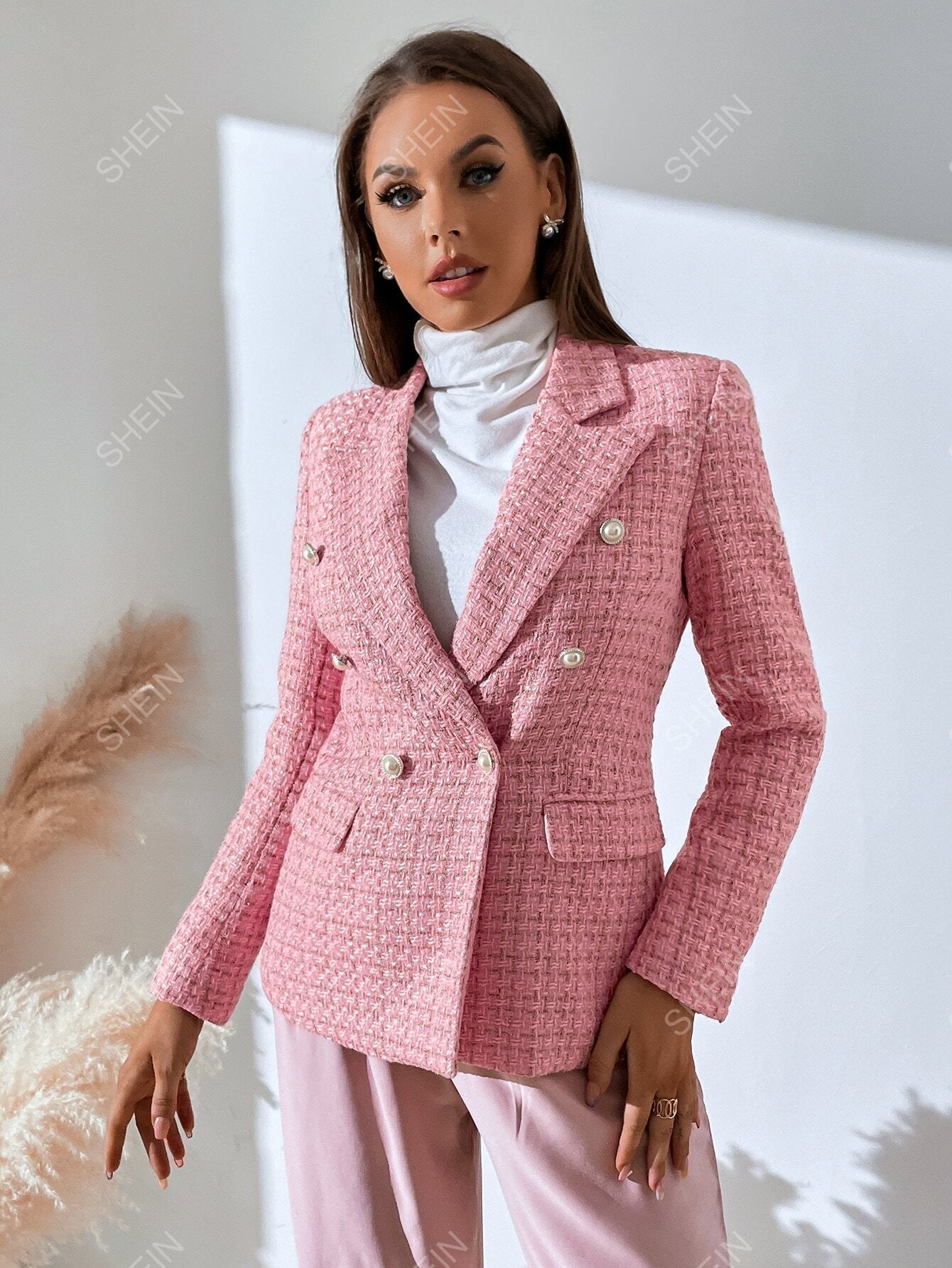 Pink tweed double-breasted blazer with notched lapels, accent buttons, and a tailored fit worn over a white turtleneck.