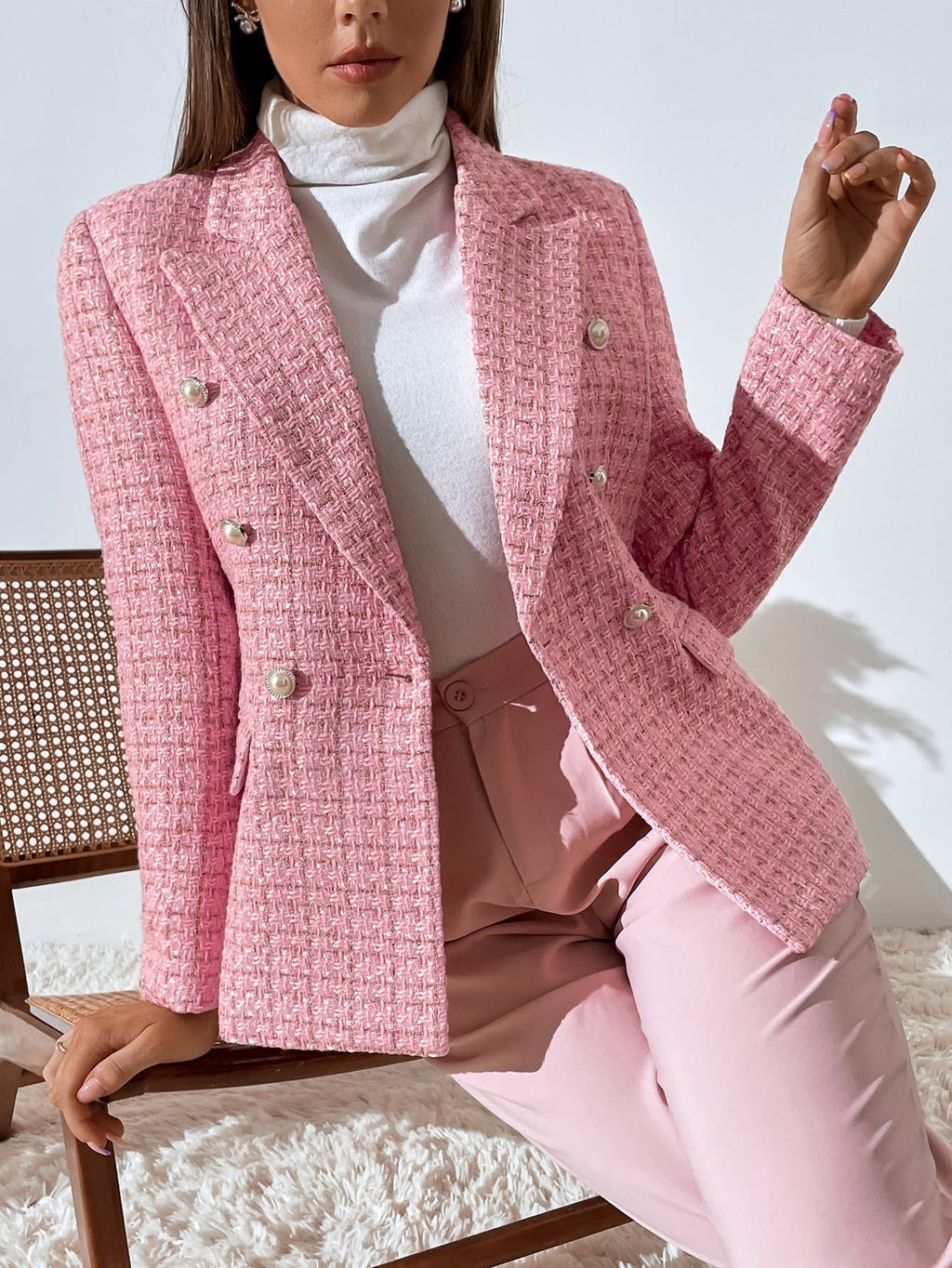 Pink tweed double-breasted blazer with notched lapels and decorative buttons, worn over a white turtleneck.