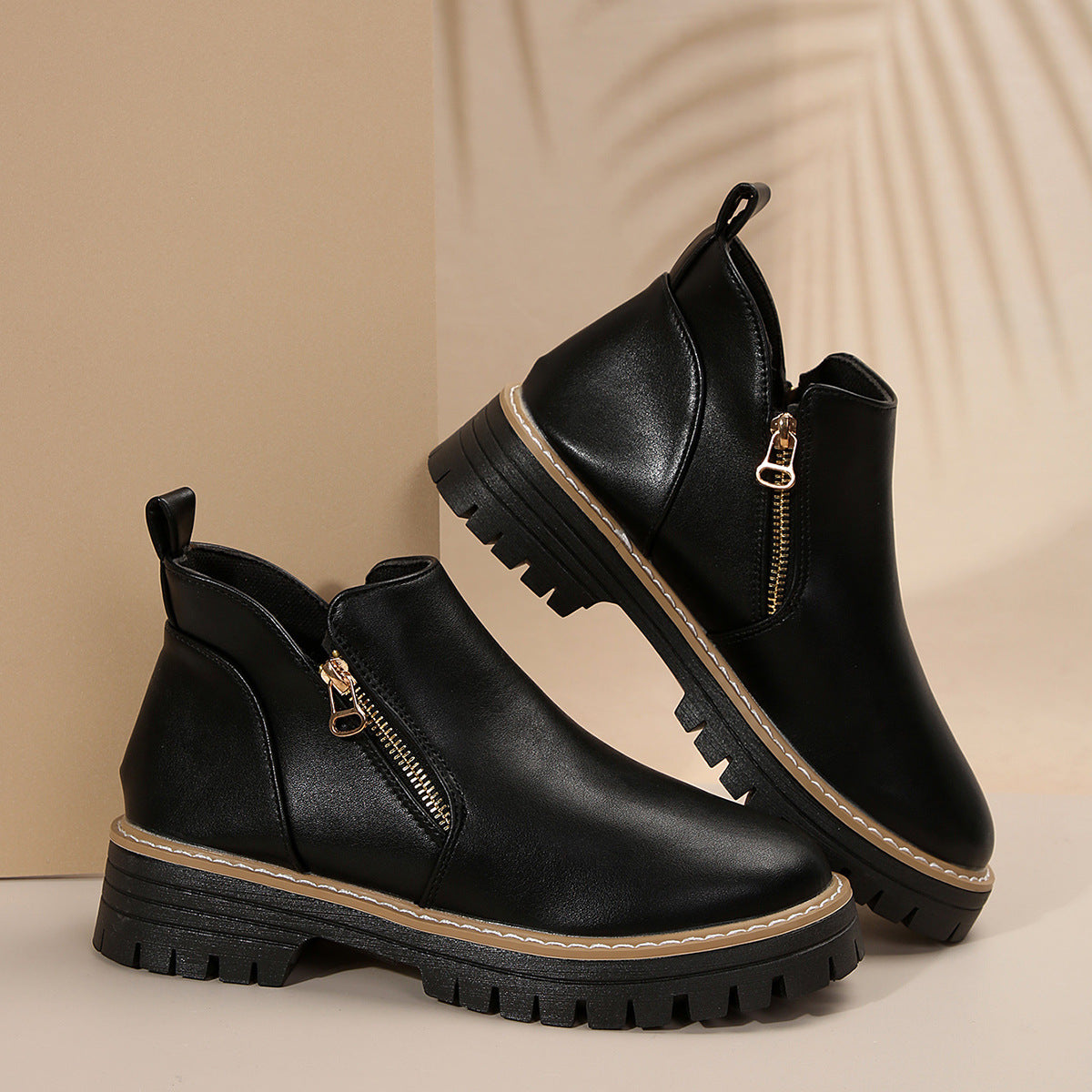 Black ankle boots with side zips, round toes, and thick notched tread soles featuring a stitched welt base.