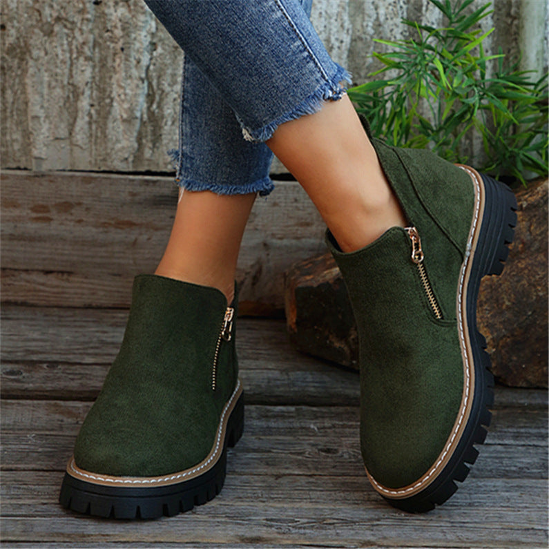 Olive green brushed ankle boots with side zips, round toes, and thick notched tread soles on a wooden surface.