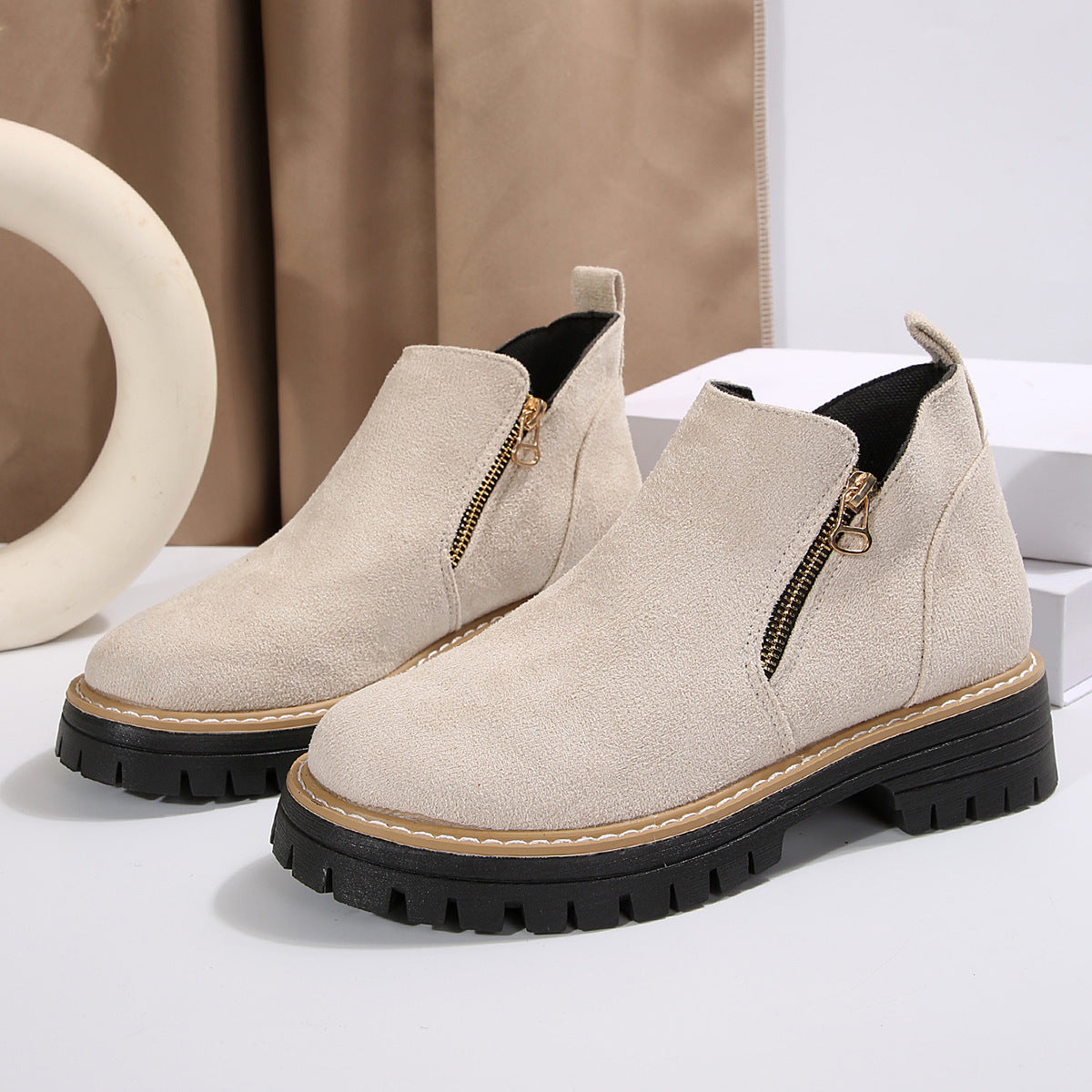 Beige brushed suede ankle boots with side zippers, round toes, and chunky black notched tread platform soles.