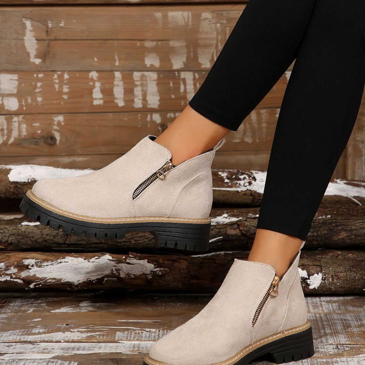Beige brushed ankle boots with side zips and chunky black notched tread soles, worn with black leggings.
