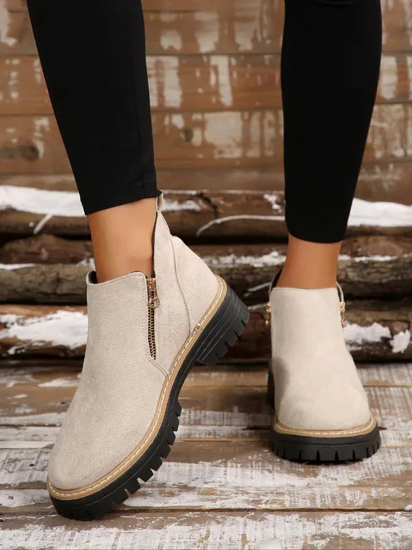 Beige brushed ankle boots with a side zip, round toe, and thick black notched tread platform sole.