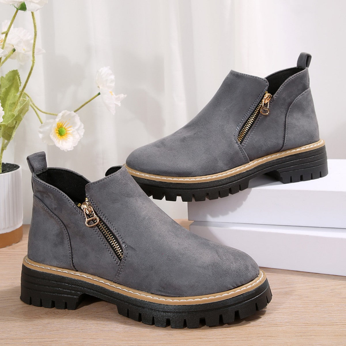Grey brushed-finish ankle boots with side zips, round toes, and thick black notched tread platform soles.