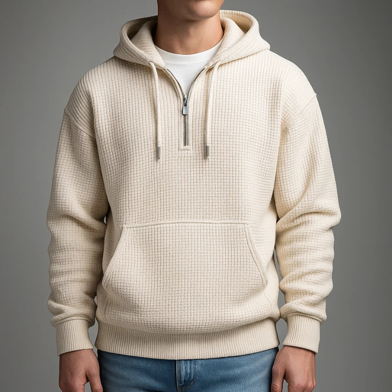 Cream waffle knit pullover hoodie with a kangaroo pocket, adjustable drawstrings, and a relaxed fit, paired with blue jeans.