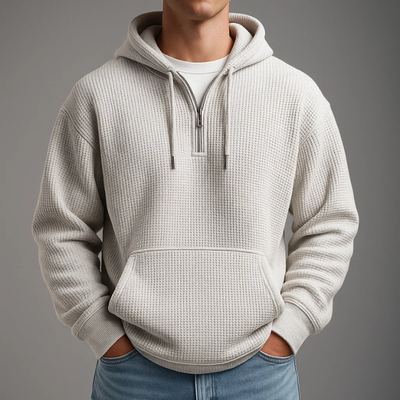 Off-white waffle knit pullover hoodie featuring a kangaroo pocket, adjustable drawstrings, and a relaxed fit, styled with blue jeans.