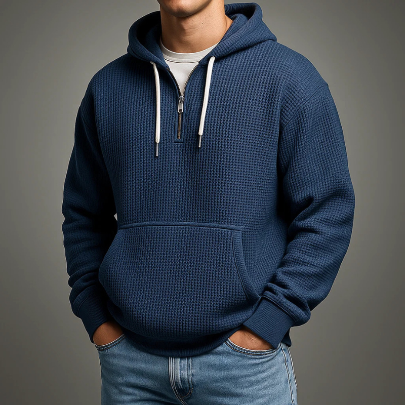 Navy waffle knit pullover hoodie featuring a kangaroo pocket, adjustable drawstrings, and a relaxed fit, paired with blue jeans.