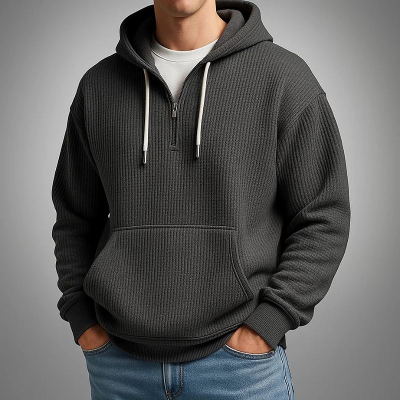 Black waffle knit pullover hoodie with a kangaroo pocket, adjustable drawstrings, and a relaxed fit, styled with blue jeans.