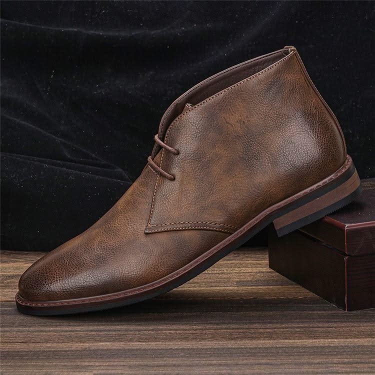 Brown grained leather chukka boot with three-eyelet lace-up closure, stitched welt, and a low stacked block heel.