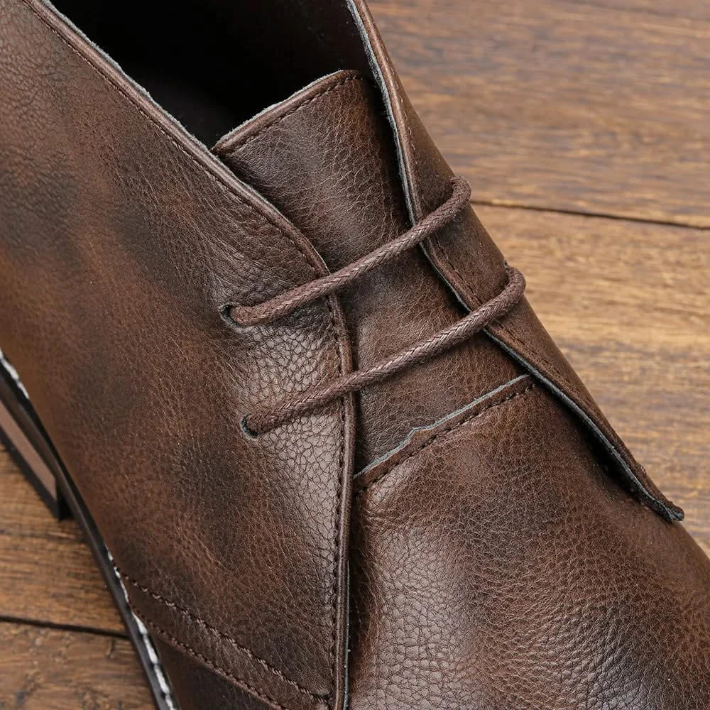 Brown grained leather chukka boots featuring a three-eyelet lace-up design, visible welt stitching, and a stacked block heel.