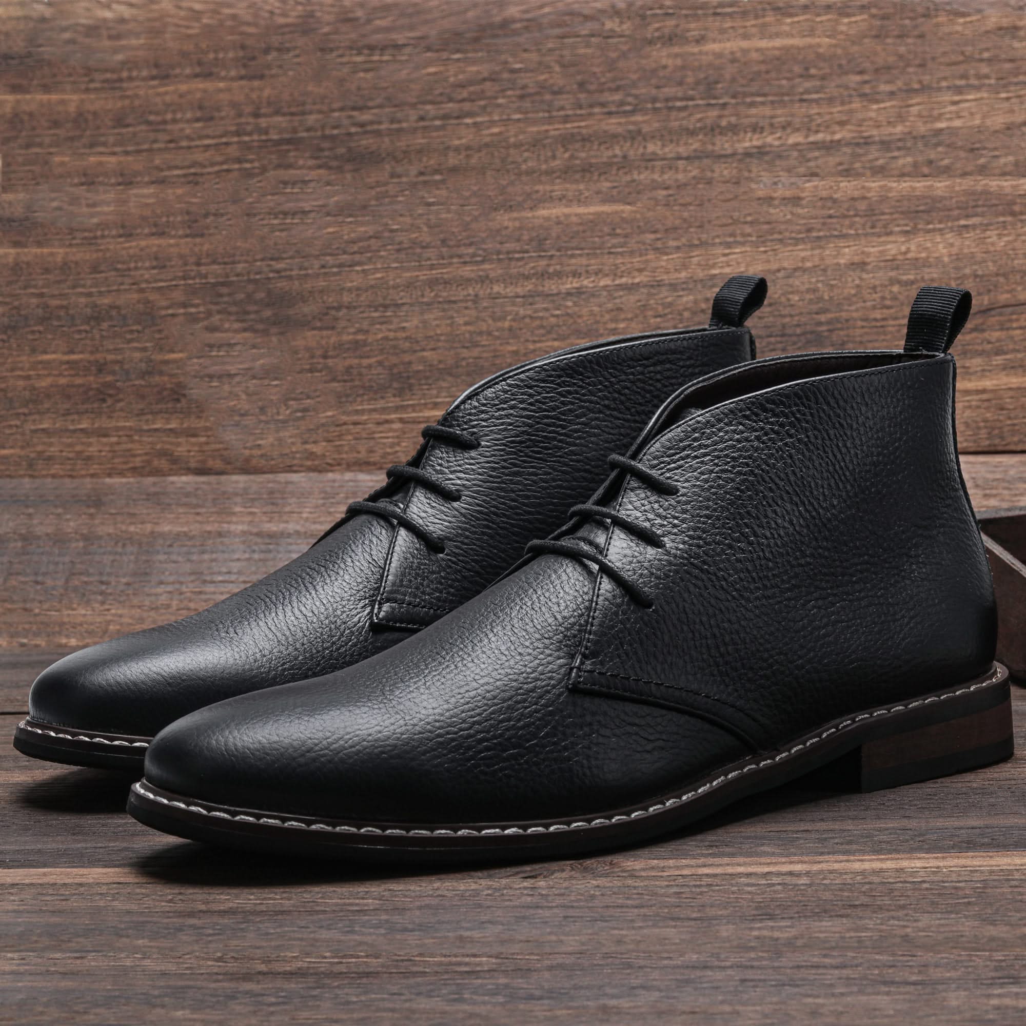Black grained leather chukka boots with three-eyelet lacing, visible welt stitching, and a low stacked block heel.
