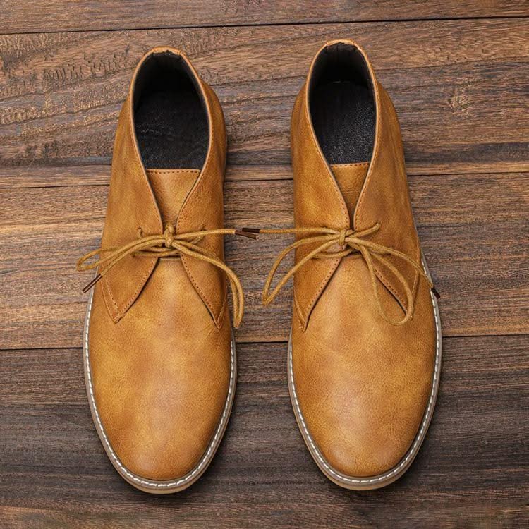 Tan grained leather chukka boots with three-eyelet lace-up closure, white welt stitching, and a clean rounded toe.