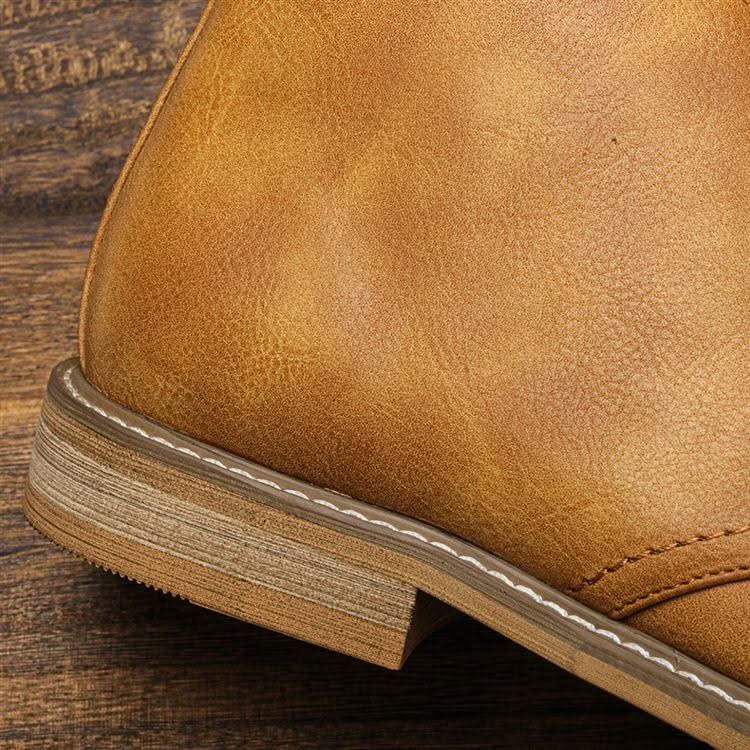 Tan grained leather chukka boot featuring a stacked low block heel and visible white perimeter welt stitching.
