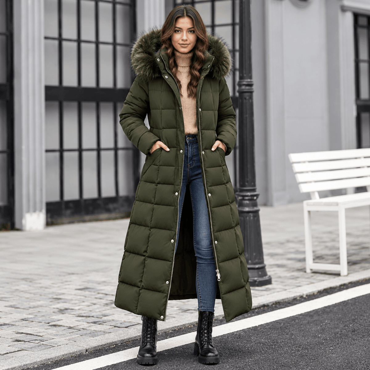 Olive green maxi puffer coat with box quilting, plush-trim hood, and snap placket worn over jeans and boots.