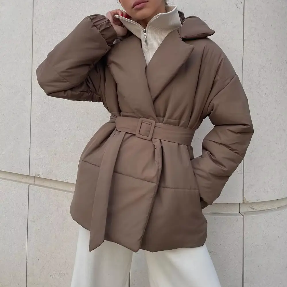 Brown belted wrap puffer jacket with notch lapels, quilted padding, and elastic cuffs worn over a zip-neck knit.