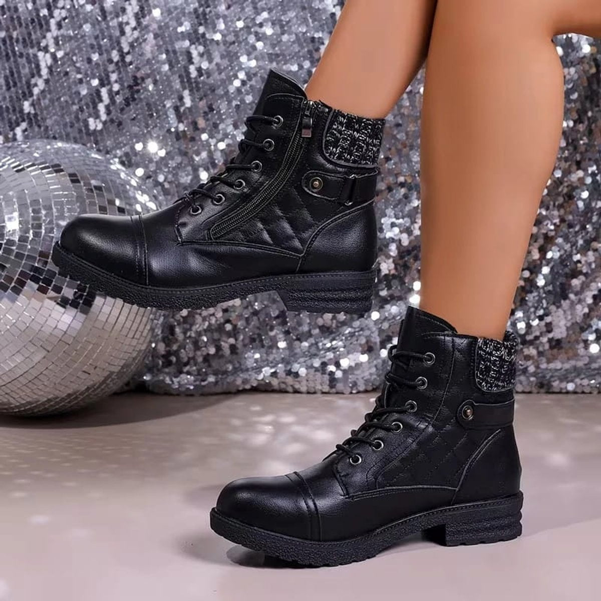 Black quilted ankle boots featuring a ribbed knit cuff, side zip closure, lace-up front, and a low block heel.