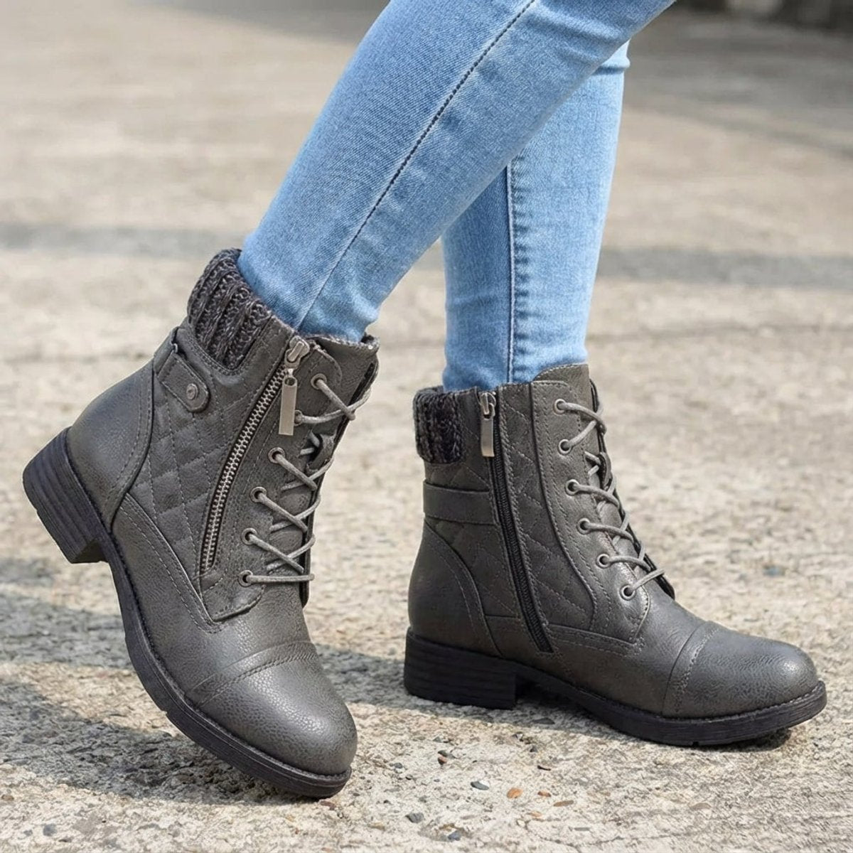 Grey quilted ankle boots with ribbed knit cuffs, side zip, lace-up front, and low block heels worn with blue jeans.