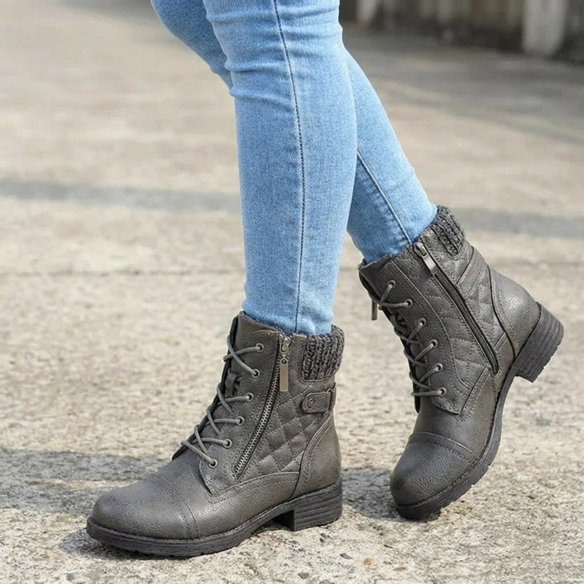 Grey quilted ankle boots with lace-up fronts, side zips, and ribbed knit cuffs worn with light wash denim jeans.