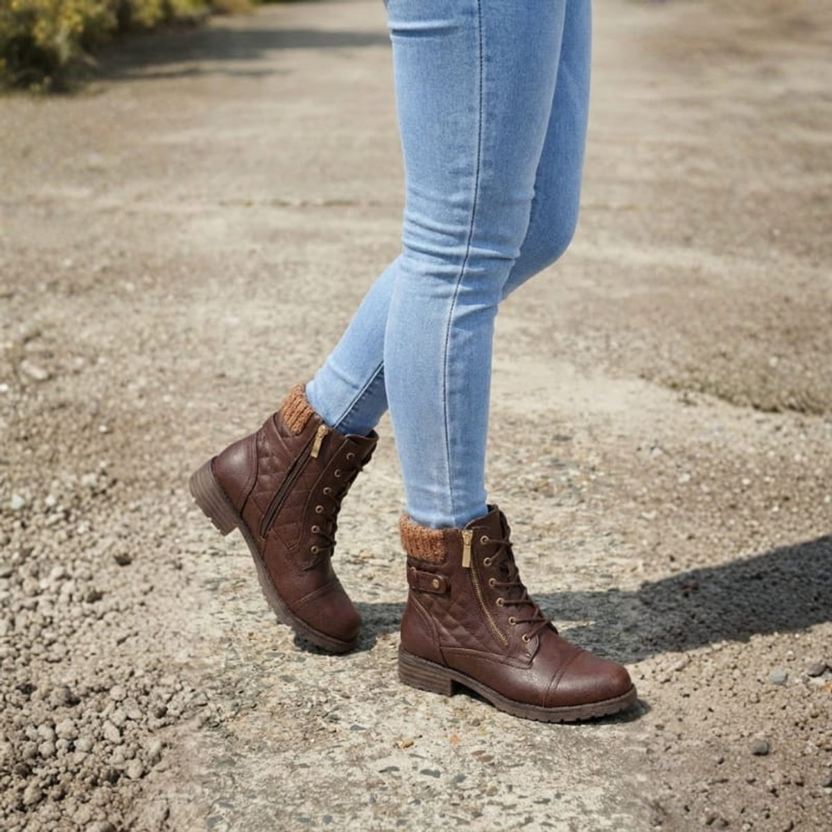 Brown quilted ankle boots with a ribbed knit cuff, side zip, and lace-up front, worn with light wash blue jeans.