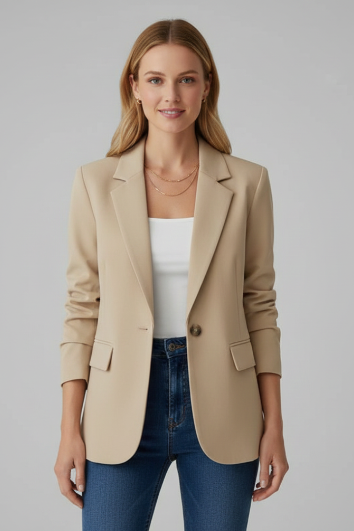 Beige single-button tailored blazer with notched lapels and structured shoulders worn over a white top and jeans.