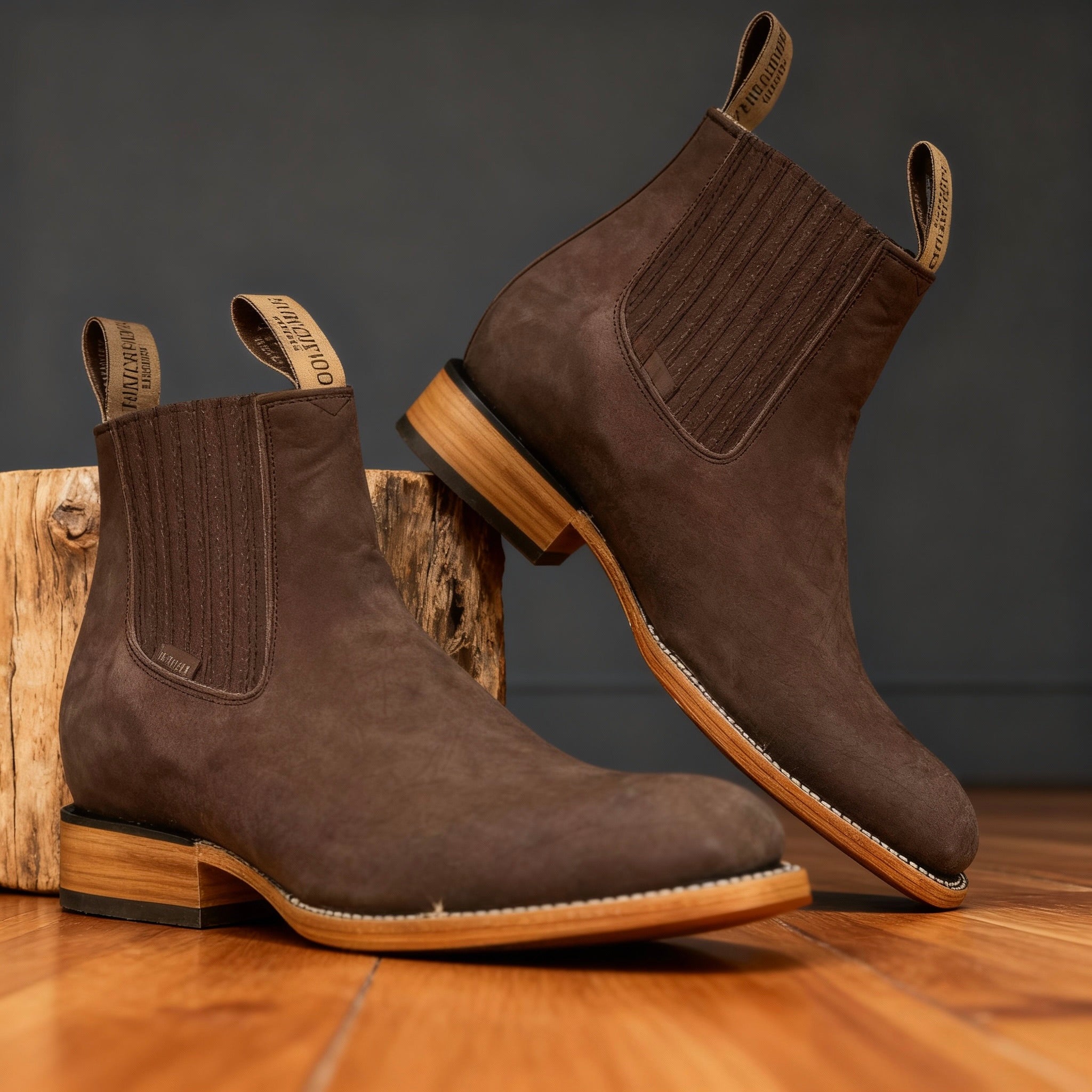 Dark brown suede western ankle boots with elastic side panels, stacked wooden heels, and reinforced welt stitching.