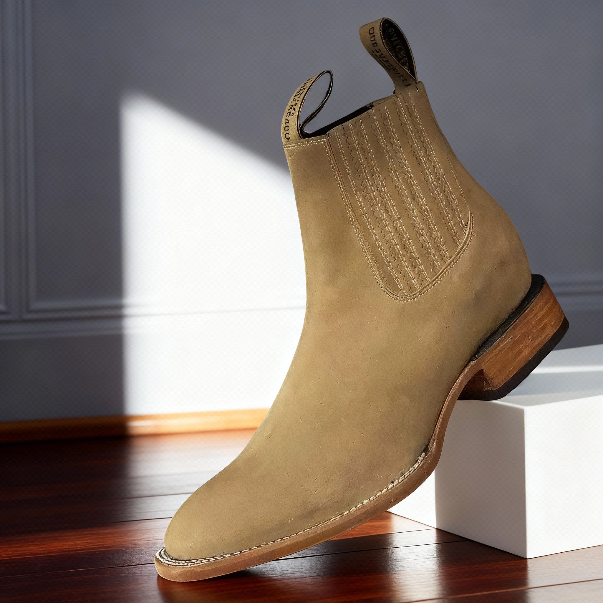 Tan suede western ankle boot with a pointed toe, elastic side panels, dual pull tabs, and a stacked wooden block heel.