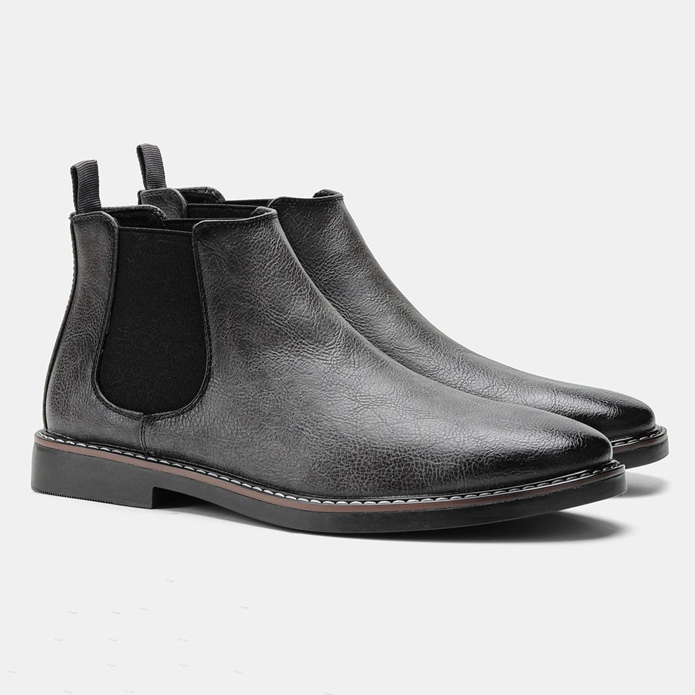 Black leather Chelsea boots with round toes, elastic side gores, dual pull tabs, and a stitched welt on a block heel.