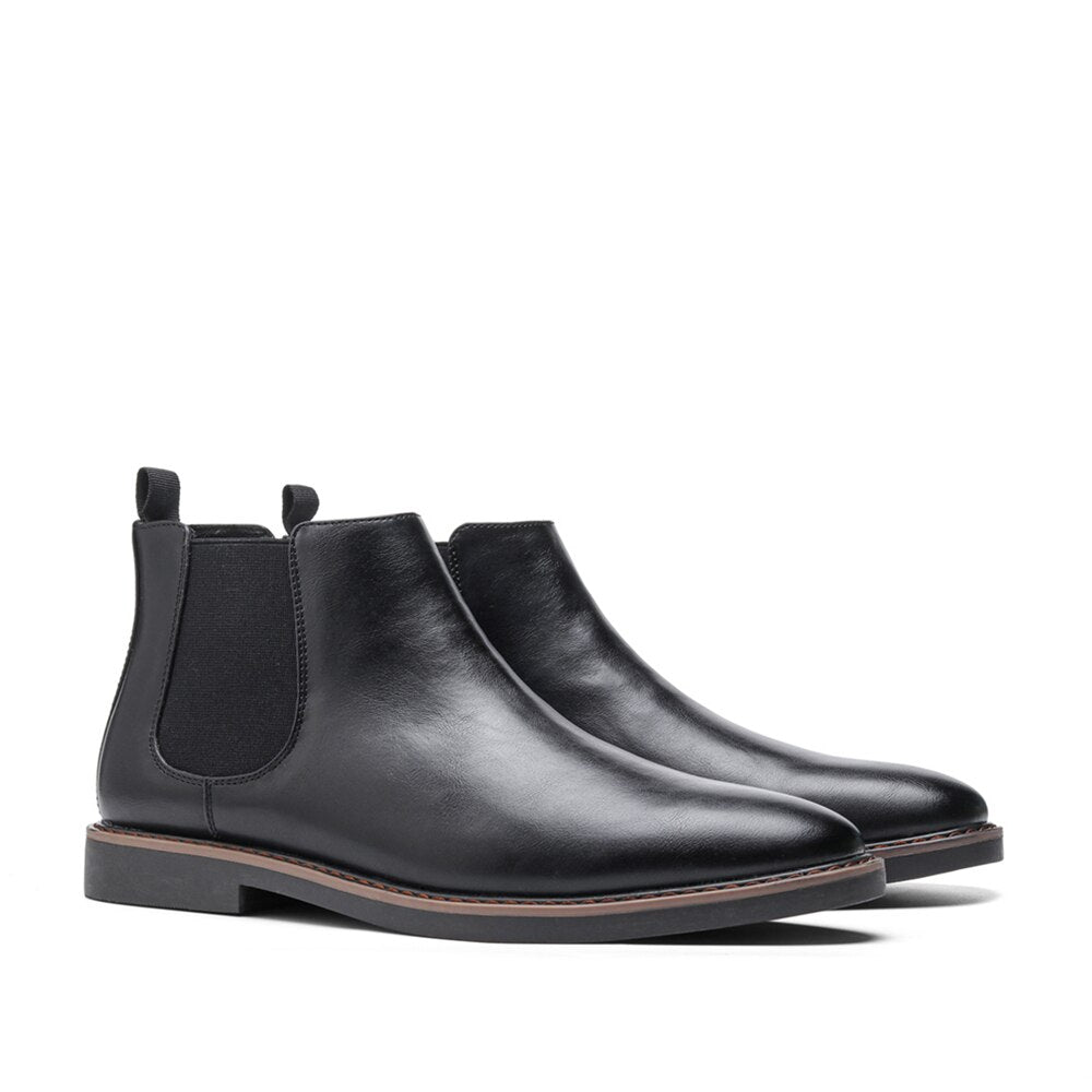 Black leather Chelsea boots with a round toe, elastic side gores, dual pull tabs, and a stitched welt on a block heel.