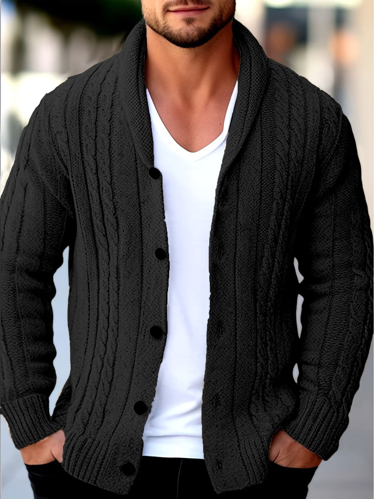 Black cable knit shawl collar cardigan with a button-front closure worn open over a white v-neck tee.