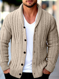 Beige cable knit shawl collar cardigan with a button-front closure, worn open over a white v-neck t-shirt.