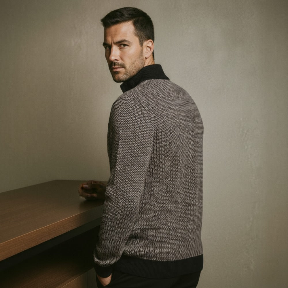 Grey birdseye knit quarter zip sweater with a black stand collar, ribbed hem, and regular fit worn by a man.