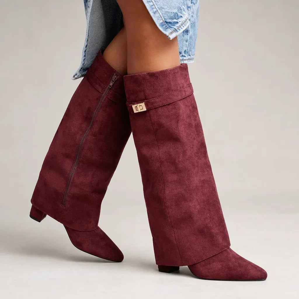Burgundy slouch knee-high suede boots with pointed toes, mid block heels, and a relaxed shaft, worn with light blue jeans.