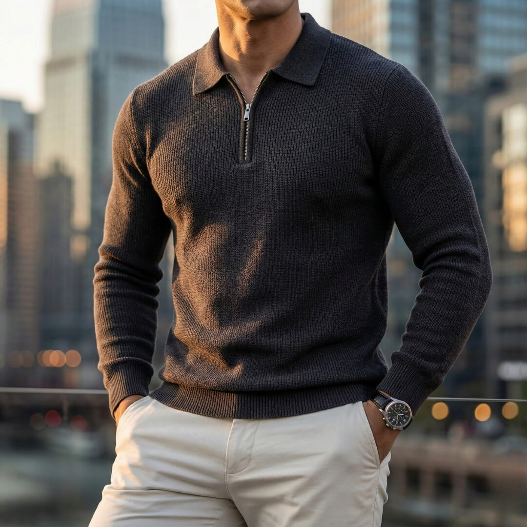 Charcoal quarter-zip knit polo sweater with a ribbed collar, long sleeves, and ribbed hem, paired with light-colored trousers.